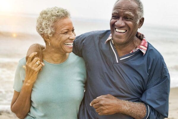 The Golden Years - Senior Couple Laughing and Embracing One Another While Walking along the Beach at Sunset