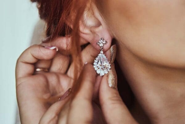 Valuable Possessions Insurance - Close-up of the Manicured Hands of a Young Woman Placing Her Expensive Earrings into Ears for a Special Occasion